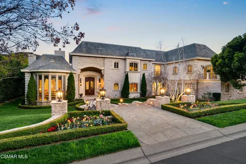 a front view of a house with a garden and trees