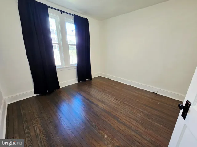 an empty room with wooden floor and window