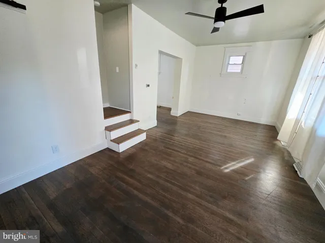 an empty room with wooden floor cabinet and windows