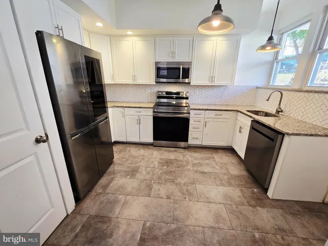 a kitchen with granite countertop a refrigerator stove and sink