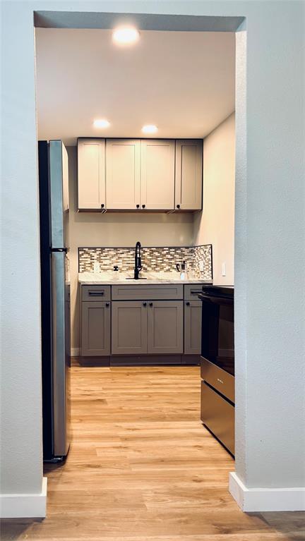4603 Junius Street, Unit 8 Dallas, TX 75246 - Photo 5 of 16 Kitchen featuring stainless steel appliances, gray cabinets, tasteful backsplash, light wood-type flooring, and recessed lighting