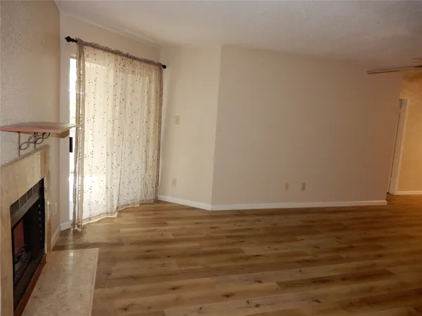 a view of empty room with wooden floor and fireplace