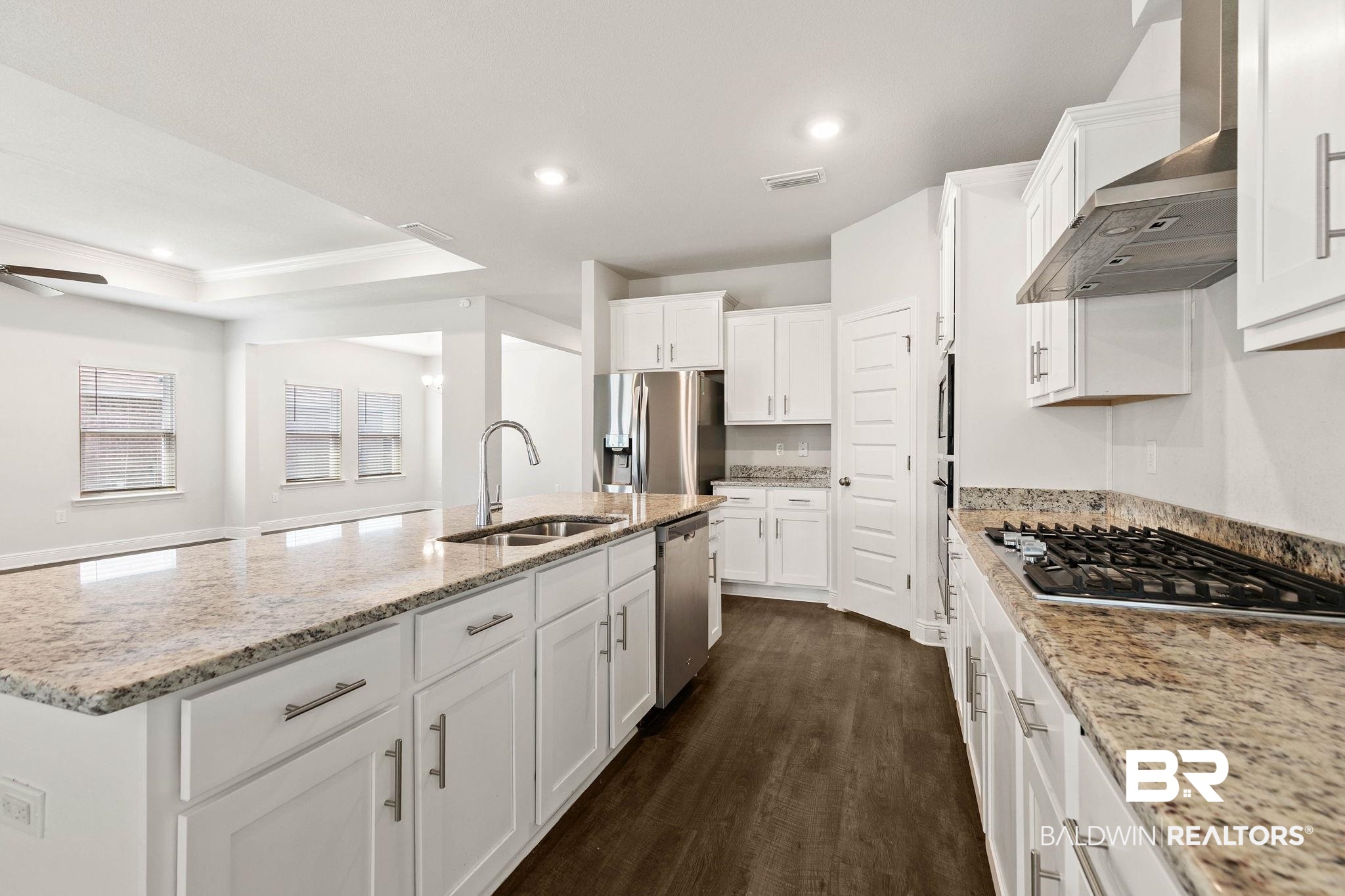 9448 Amethyst Drive Daphne, AL 36526 - Photo 17 of 61 Kitchen featuring a raised ceiling, an island with sink, ornamental molding, white cabinetry, and dark wood-style floors