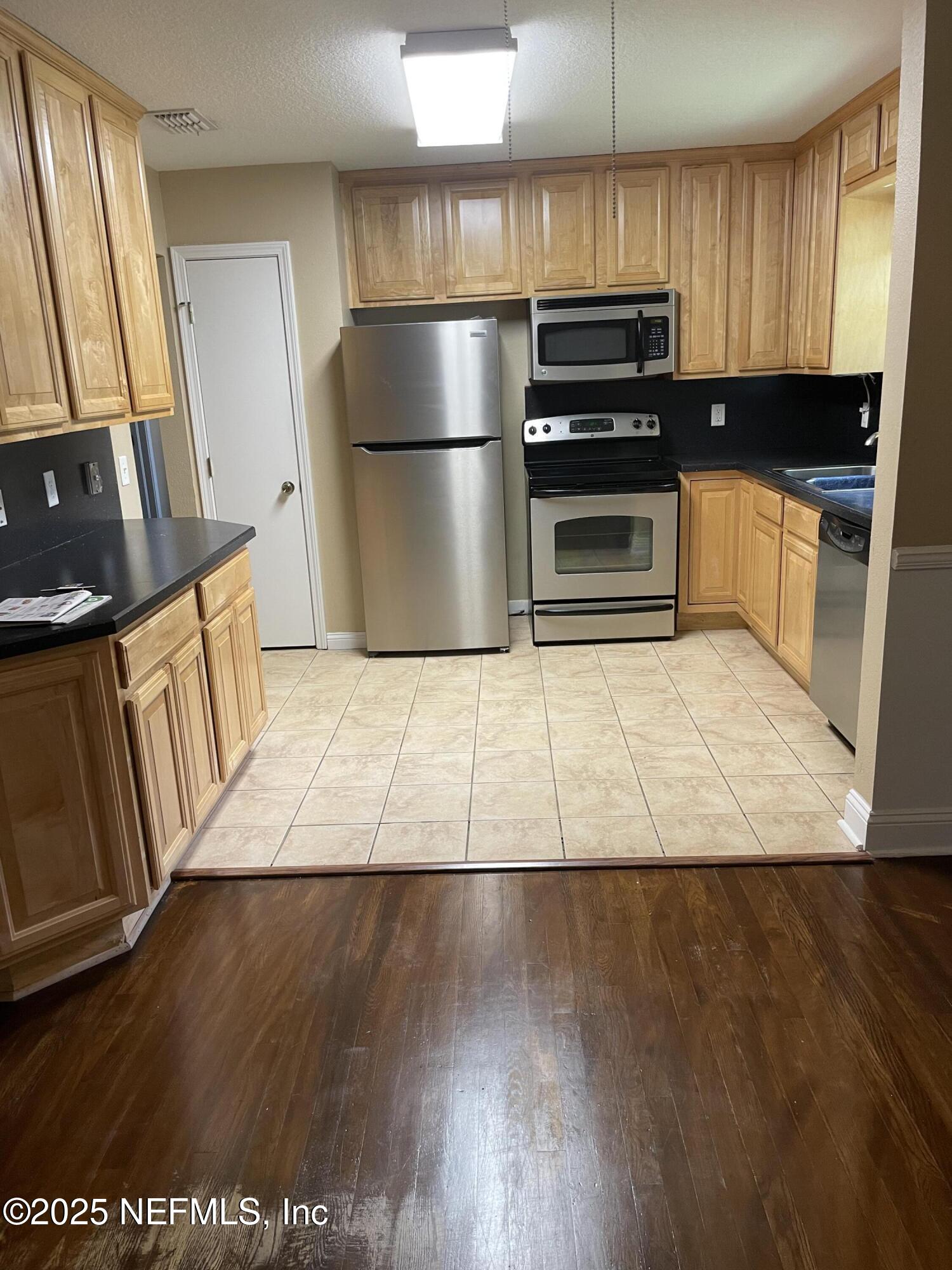 6938 Corkwood Road Jacksonville, FL 32277 - Photo 9 of 25 a kitchen with granite countertop a refrigerator and a stove top oven