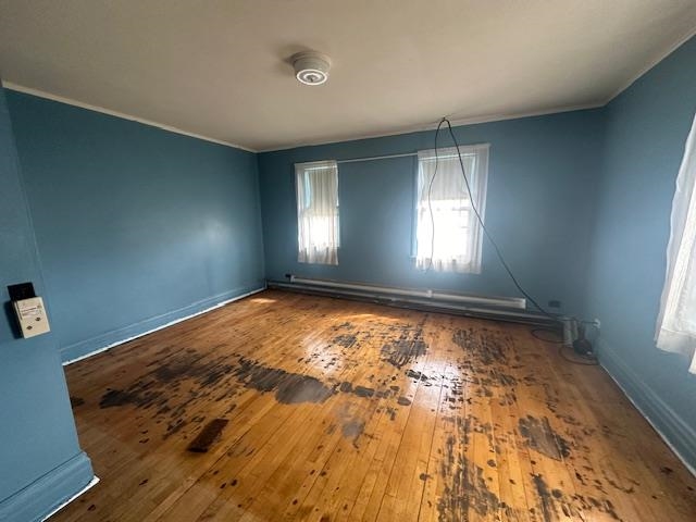 412 Monroe Street Eveleth, MN 55734 - Photo 2 of 22 Empty room with hardwood / wood-style floors, ornamental molding, and a baseboard heating unit