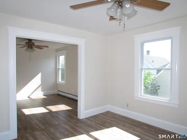 a view of an empty room with wooden floor and a window