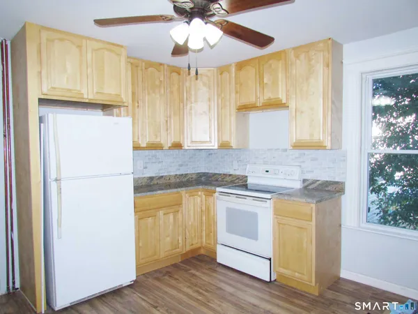 a kitchen with stainless steel appliances granite countertop a refrigerator a sink dishwasher a stove and white countertops with wooden floor