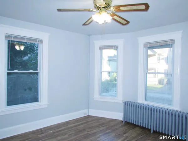 a view of an empty room with wooden floor and a window