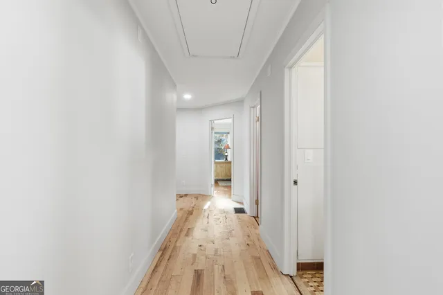 a view of a hallway with wooden floor and a bathroom
