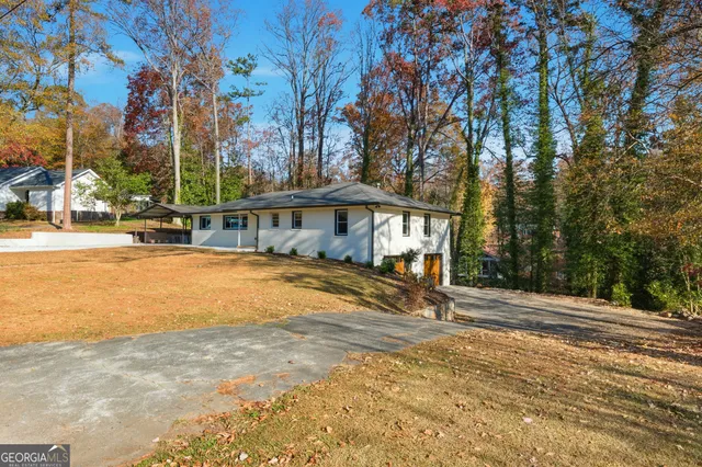 a front view of a house with a yard covered with trees