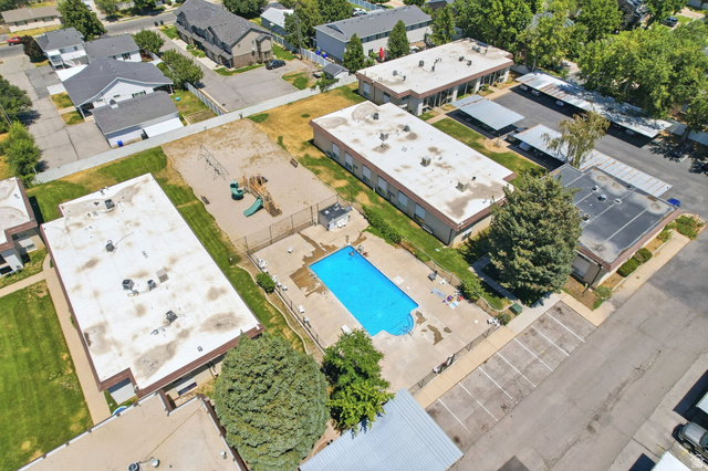 314 West Center Street, Unit F102 Bountiful, UT 84010 - Photo 25 of 29 Outdoor swimming pool with concrete surround, fenced playground area, multiple residential buildings, and dedicated parking spaces