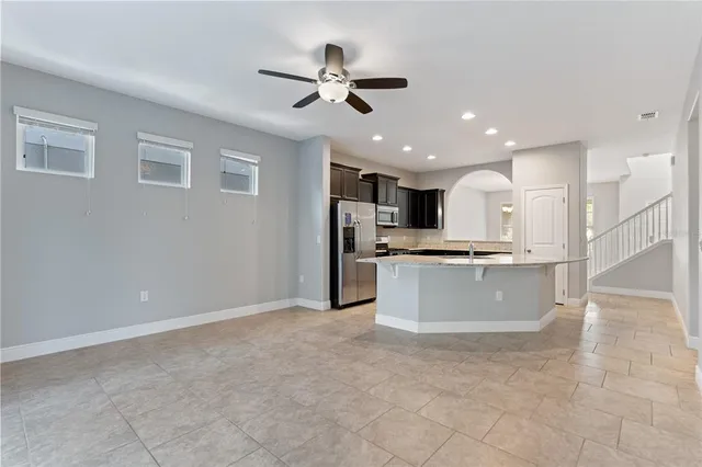 a living room with kitchen island furniture and a ceiling fan