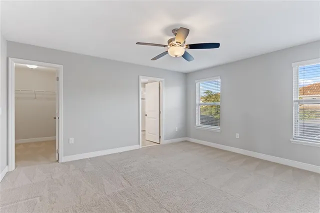 an empty room with chandelier fan and windows