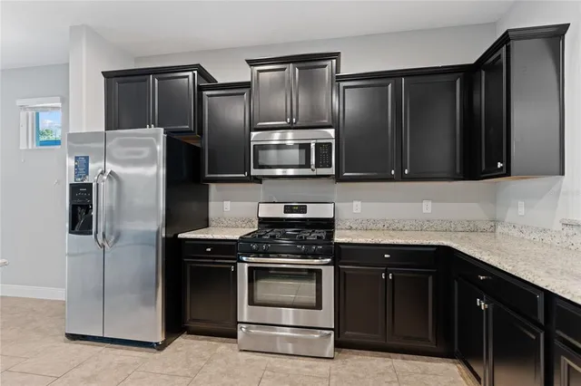 a large kitchen with stainless steel appliances granite countertop a large counter top a stove and a refrigerator