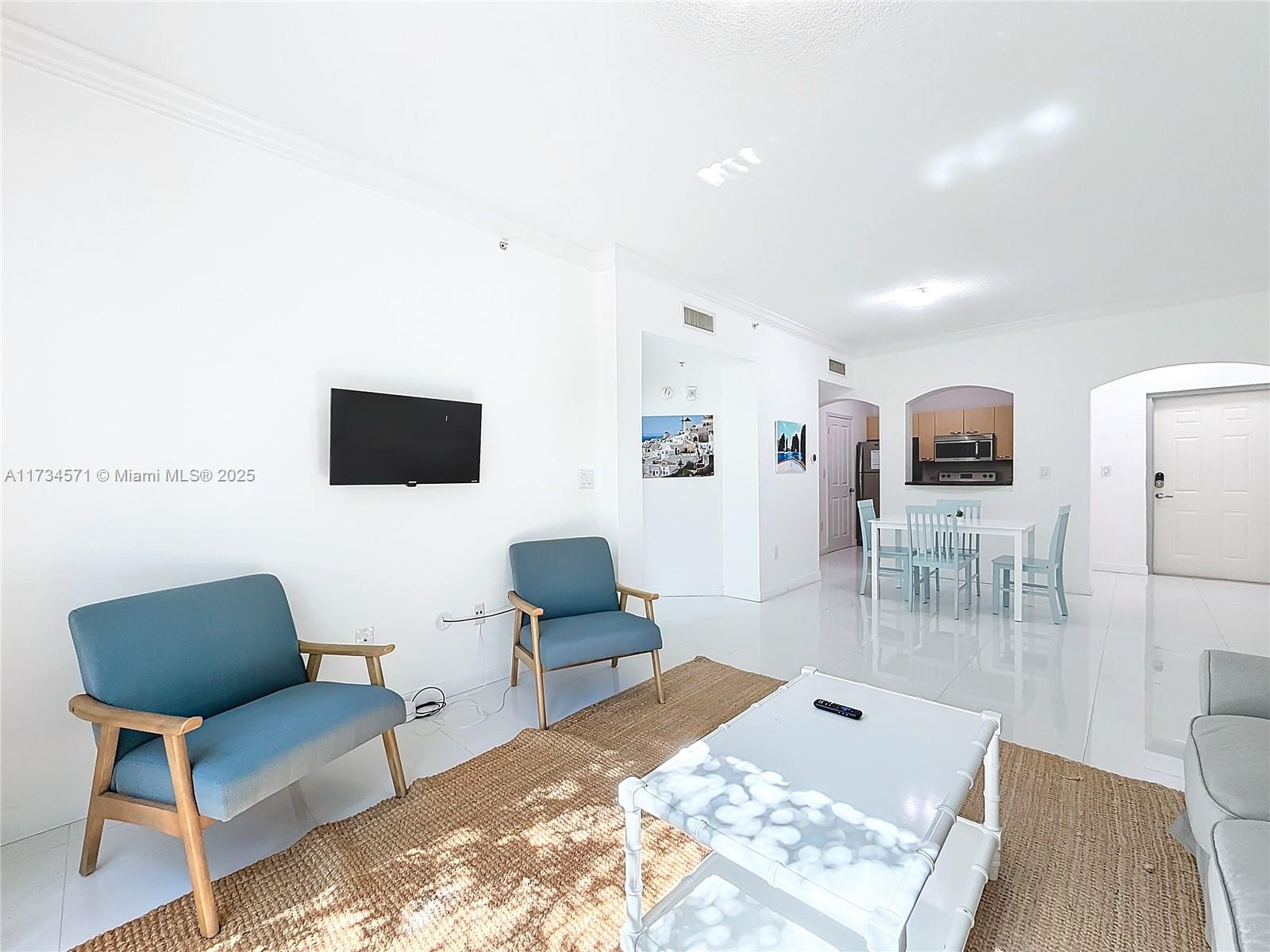 9172 Collins Avenue, Unit 414 Surfside, FL 33154 - Photo 16 of 23 a living room with furniture and a flat screen tv