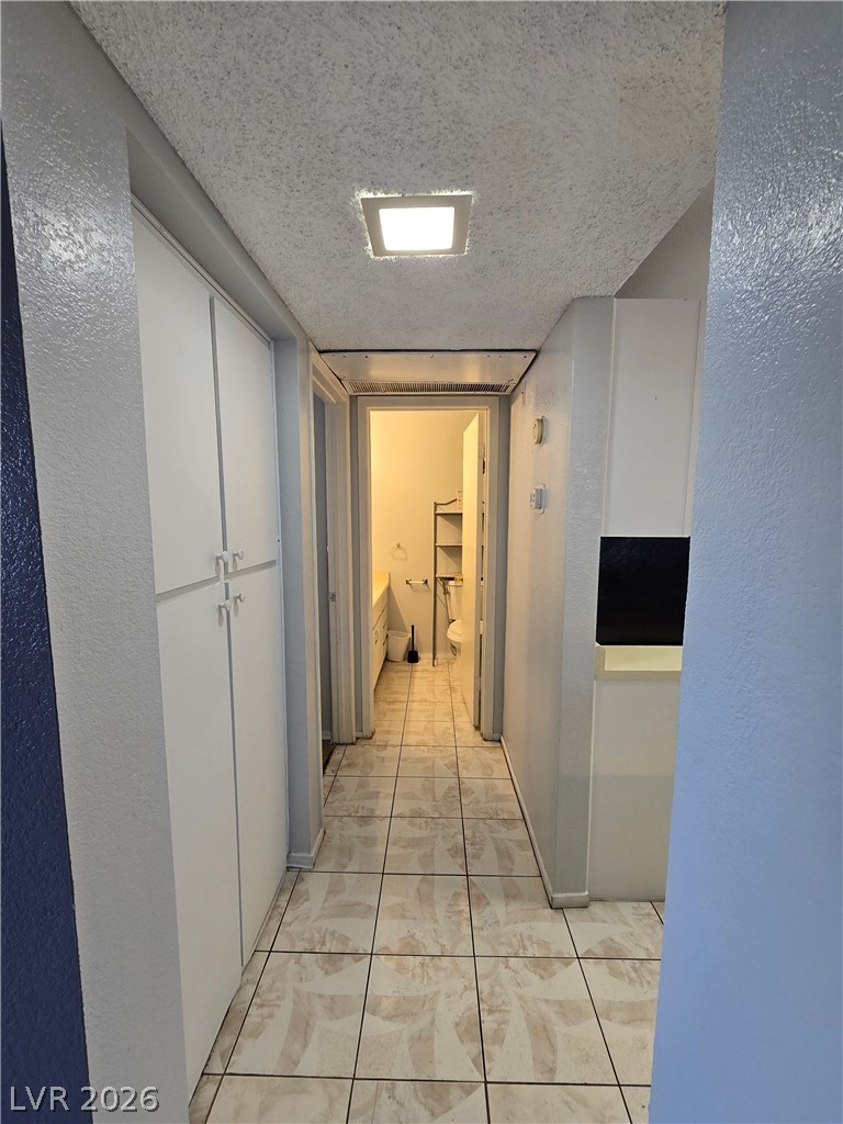 6750 Del Rey Avenue, Unit 133 Las Vegas, NV 89146 - Photo 21 of 34 A well-lit hallway with durable tile flooring leads to an accessible bathroom.