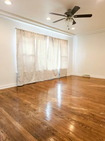 an empty room with wooden floor and windows with curtains