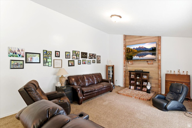 5321 South 3100th Street West Roy, UT 84067 - Photo 30 of 64 Living area featuring a brick and wood-paneled accent wall, a brick hearth, and wall-to-wall carpeting