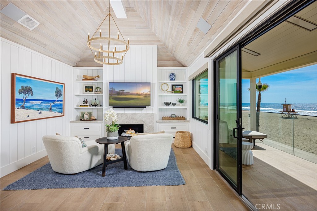 6110 West Oceanfront Newport Beach, CA 92663 - Photo 17 of 33 a living room with furniture a flat screen tv and a chandelier