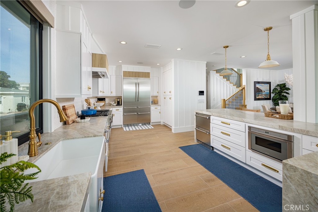 6110 West Oceanfront Newport Beach, CA 92663 - Photo 6 of 33 a large kitchen with stainless steel appliances kitchen island granite countertop a refrigerator a stove a sink and a dining table with wooden floor