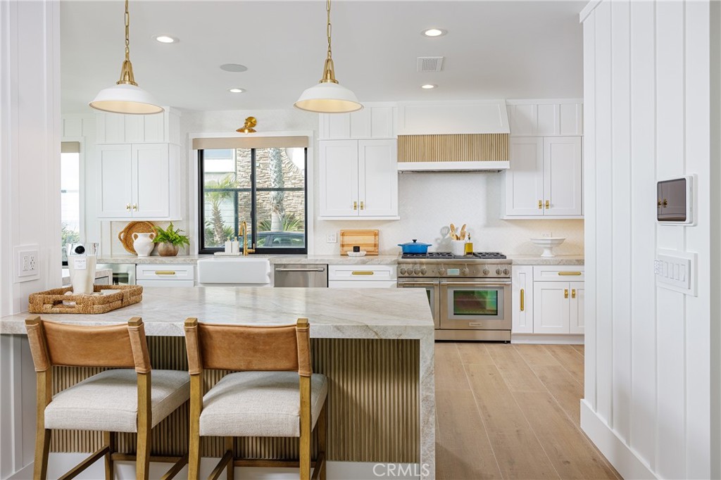 6110 West Oceanfront Newport Beach, CA 92663 - Photo 8 of 33 a kitchen with stainless steel appliances granite countertop a stove top oven a sink dishwasher and white cabinets with wooden floor