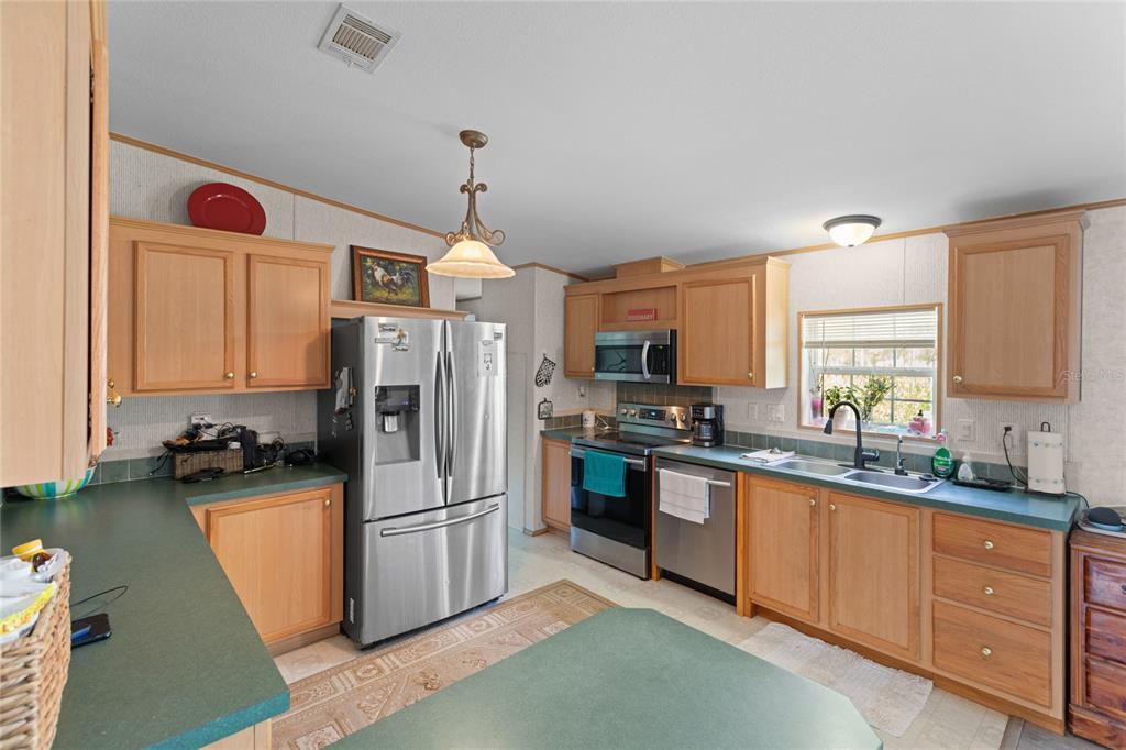 5670 Acadia Street Keystone Heights, FL 32656 - Photo 34 of 65 a kitchen with refrigerator a sink and cabinets