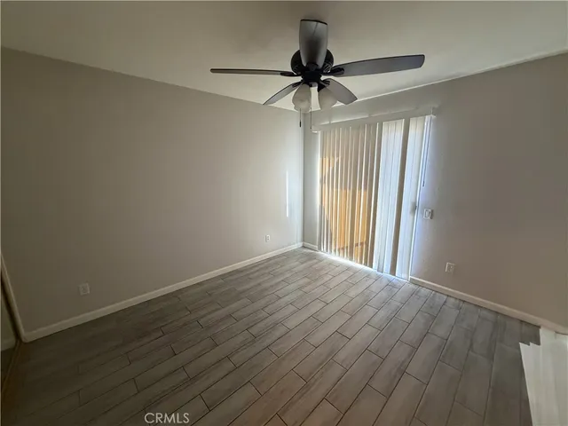 a view of empty room with wooden floor and fan