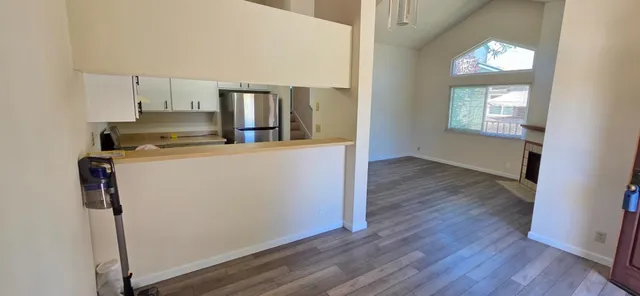 an empty room with wooden floor mirror and windows