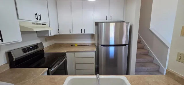 a kitchen with a refrigerator sink and cabinets