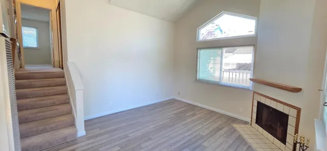 an empty room with wooden floor closet and windows