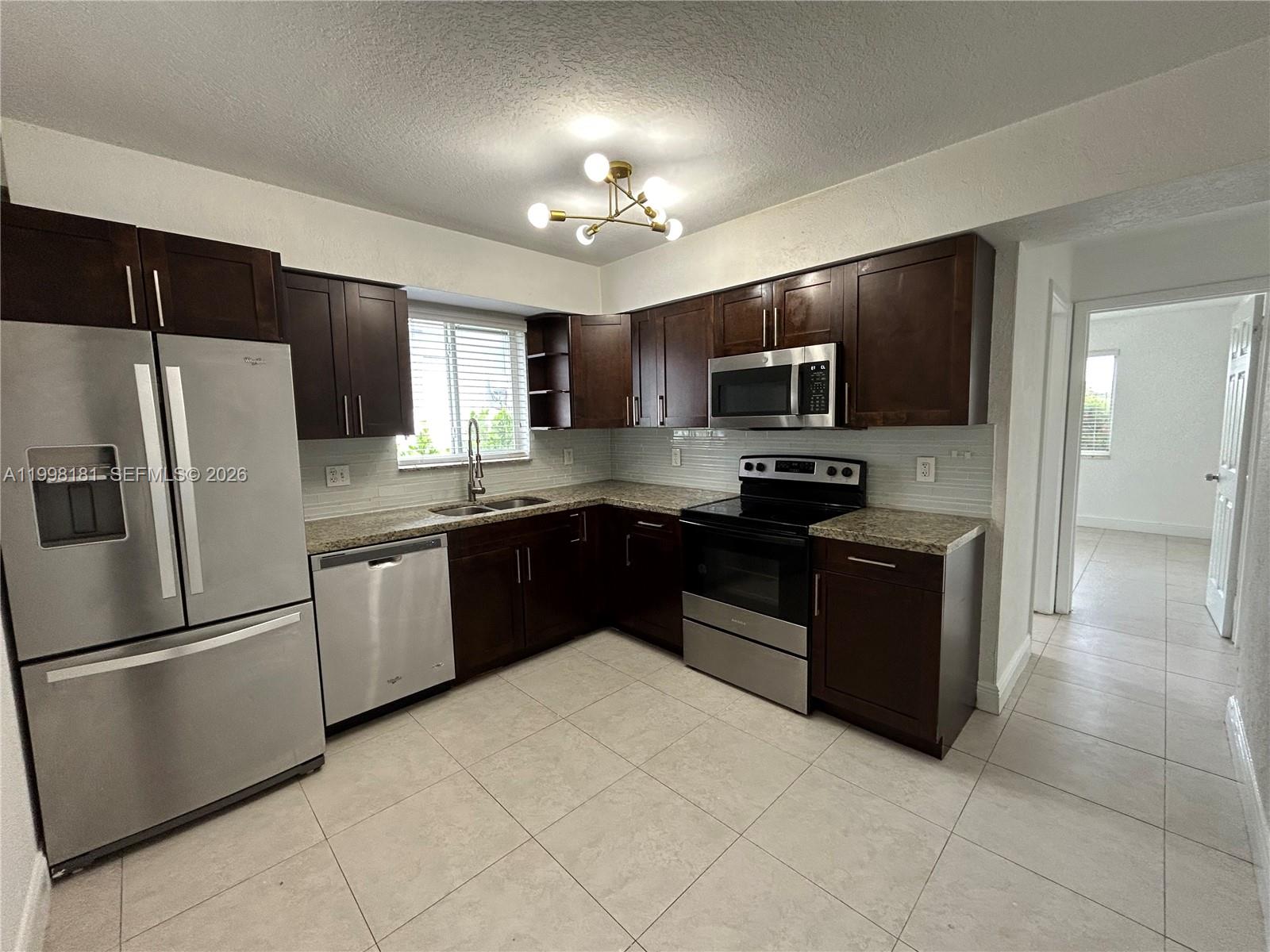 2804 Southwest 35th Avenue, Unit 2804 Miami, FL 33133 - Photo 6 of 22 a kitchen with granite countertop stainless steel appliances and a refrigerator