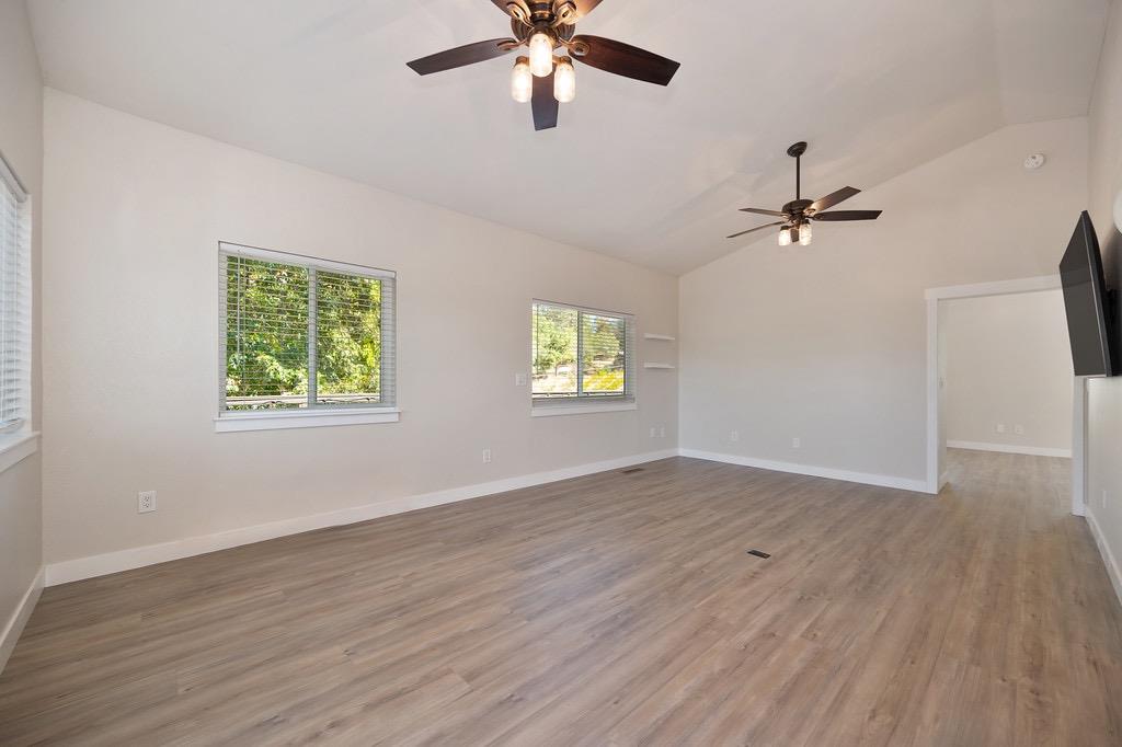 5205 Rooster Lane Somerset, CA 95684 - Photo 46 of 98 an empty room with wooden floor chandelier fan and windows