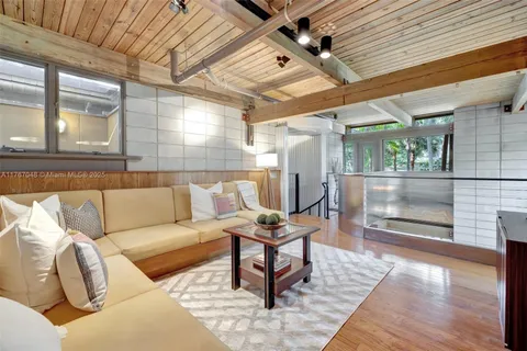 a view of a house with brick walls and a small yard with plants and a large tree