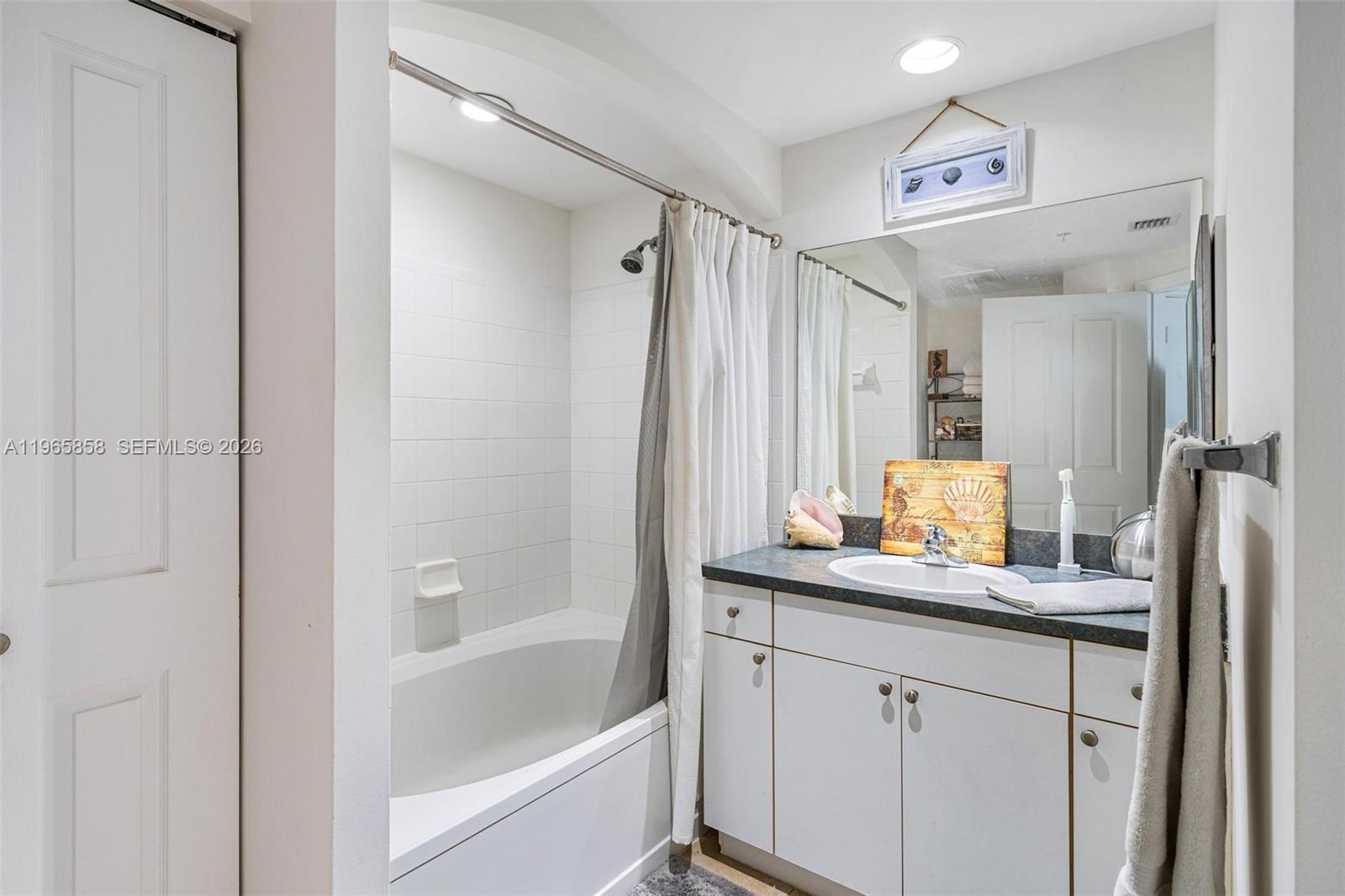 9172 Collins Avenue, Unit 210 Surfside, FL 33154 - Photo 19 of 41 a bathroom with a granite countertop sink mirror and a bathtub