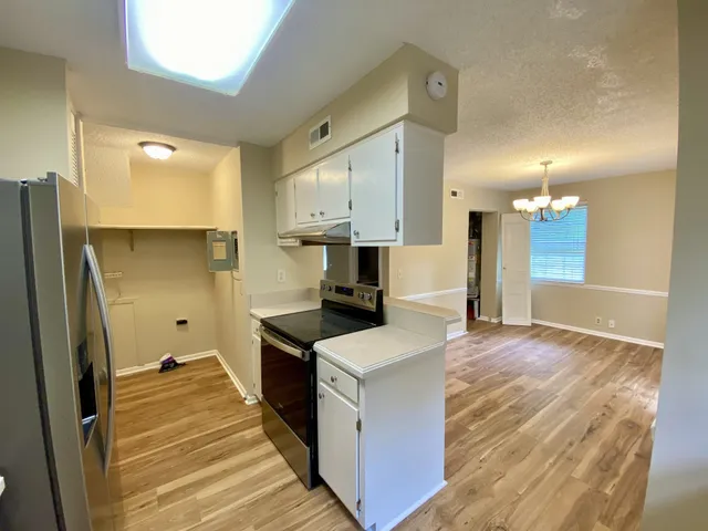 a kitchen with kitchen island a counter top space a sink a refrigerator and wooden floor