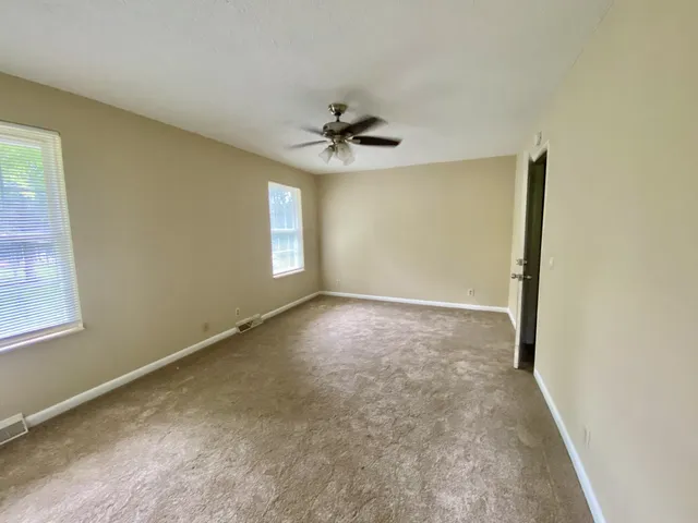 an empty room with windows and fan