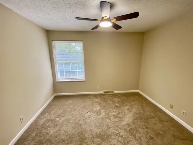 an empty room with a window and a fan