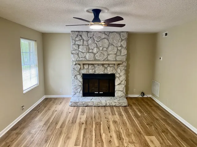 a living room with a fireplace furniture a rug and a window