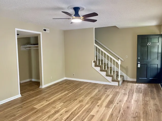 wooden floor in a hall with a window and a kitchen