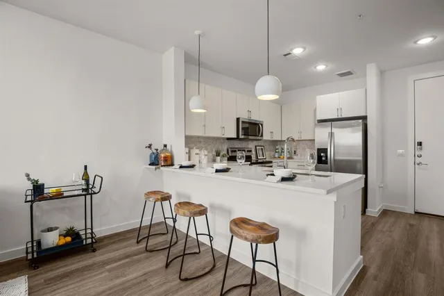 a kitchen with kitchen island a stove a chandelier a sink and a refrigerator