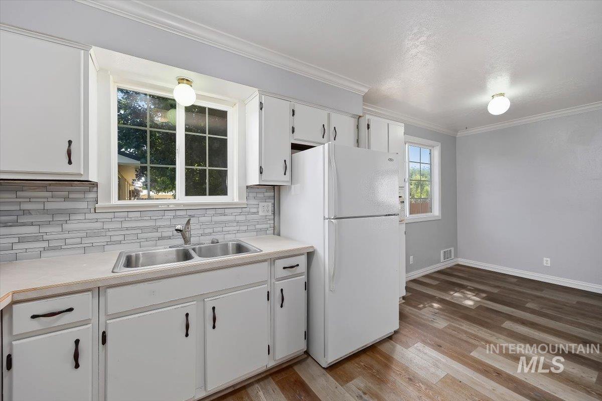 1940 Q Street Heyburn, ID 83336 - Photo 16 of 30 Kitchen featuring white cabinetry, a double basin stainless steel sink, and a tiled backsplash