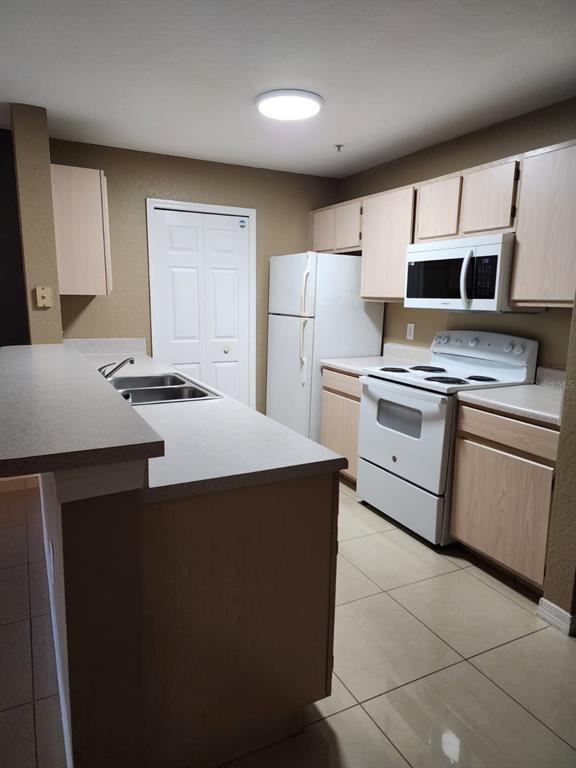 5483 Vineland Road, Unit 10107 Orlando, FL 32811 - Photo 4 of 17 a kitchen with a stove a sink and a refrigerator