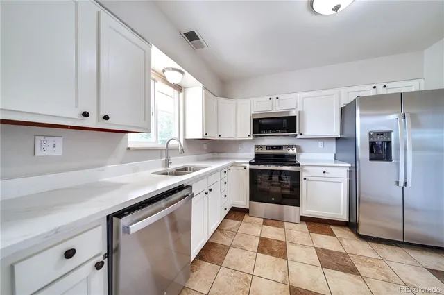 a kitchen with stainless steel appliances granite countertop a refrigerator and a stove top oven