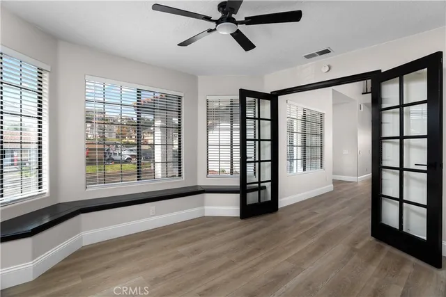 a view of empty room with wooden floor and fan