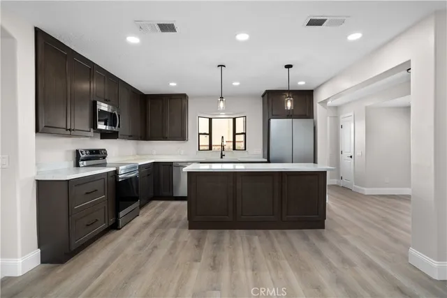 a large kitchen with wooden floors and stainless steel appliances