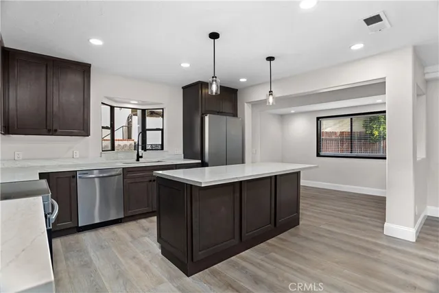 a kitchen with kitchen island granite countertop a sink cabinets and wooden floor