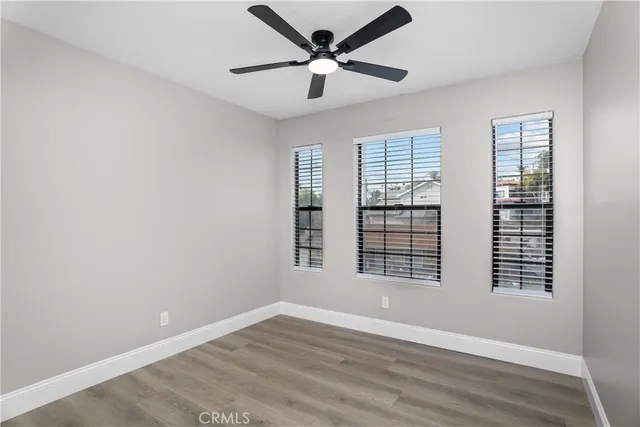 a view of an empty room with a window and wooden floor
