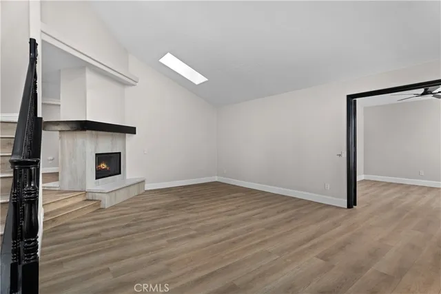 a view of an empty room with wooden floor and a fireplace
