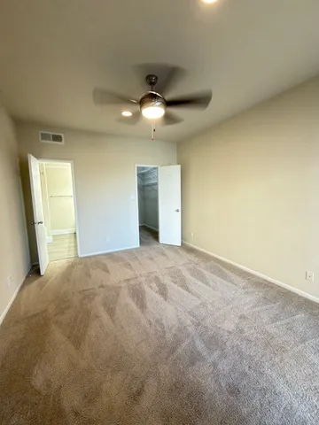 a view of an empty room and chandelier fan