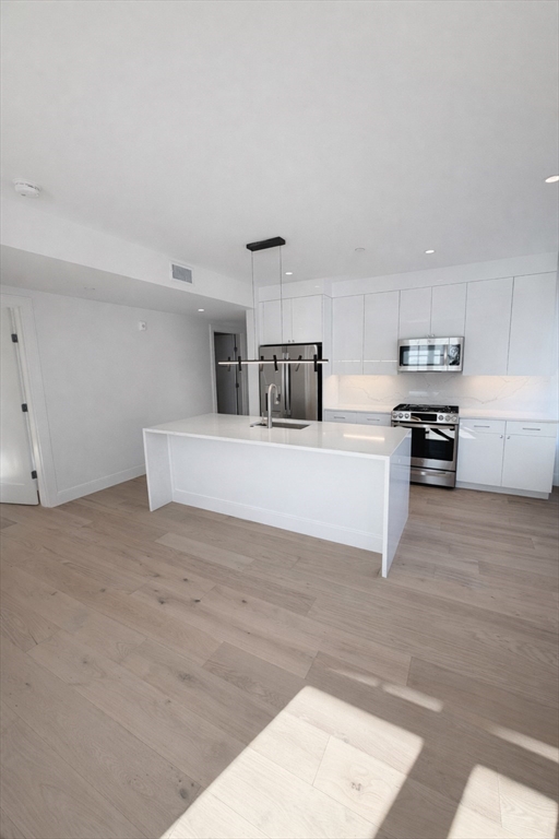 65 L Street, Unit 9 Boston, MA 02127 - Photo 2 of 8 a kitchen with granite countertop a stove top oven and cabinets